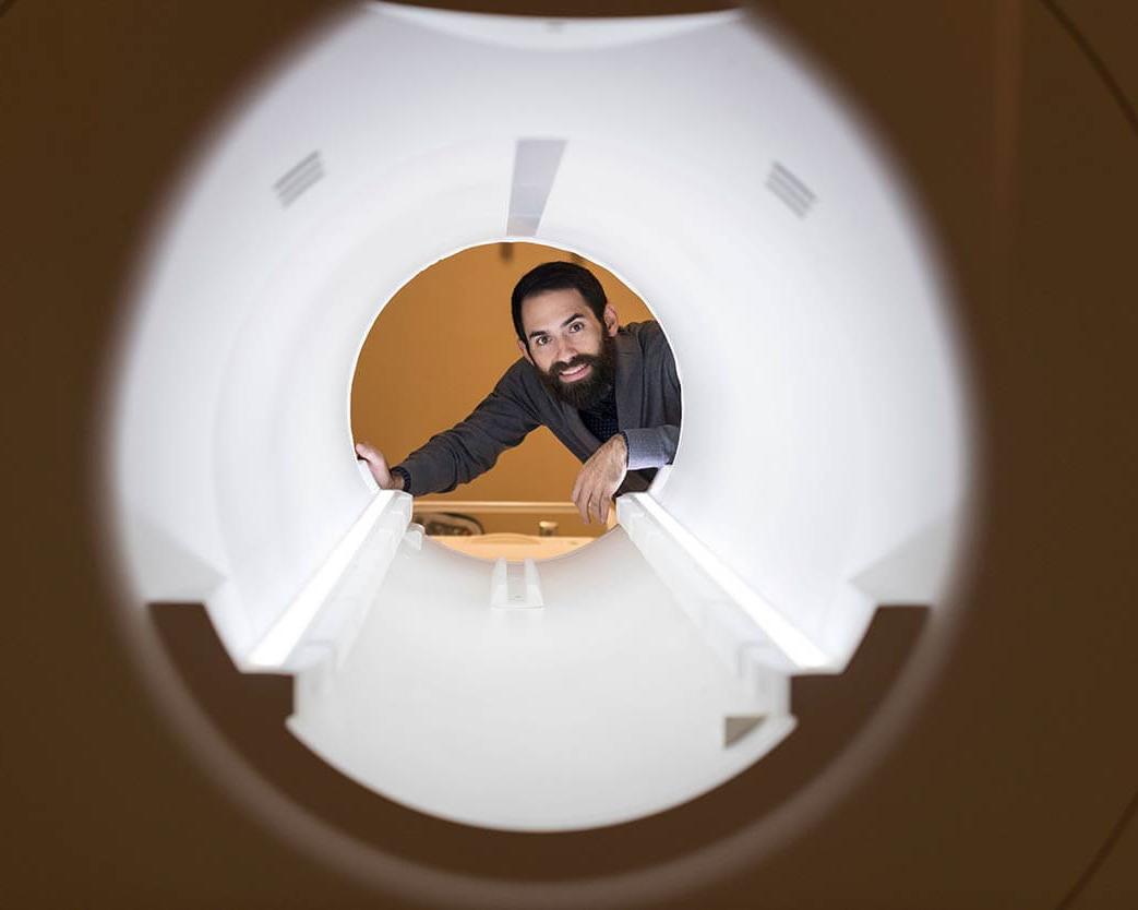 Researcher smiles while looking through an MRI machine
