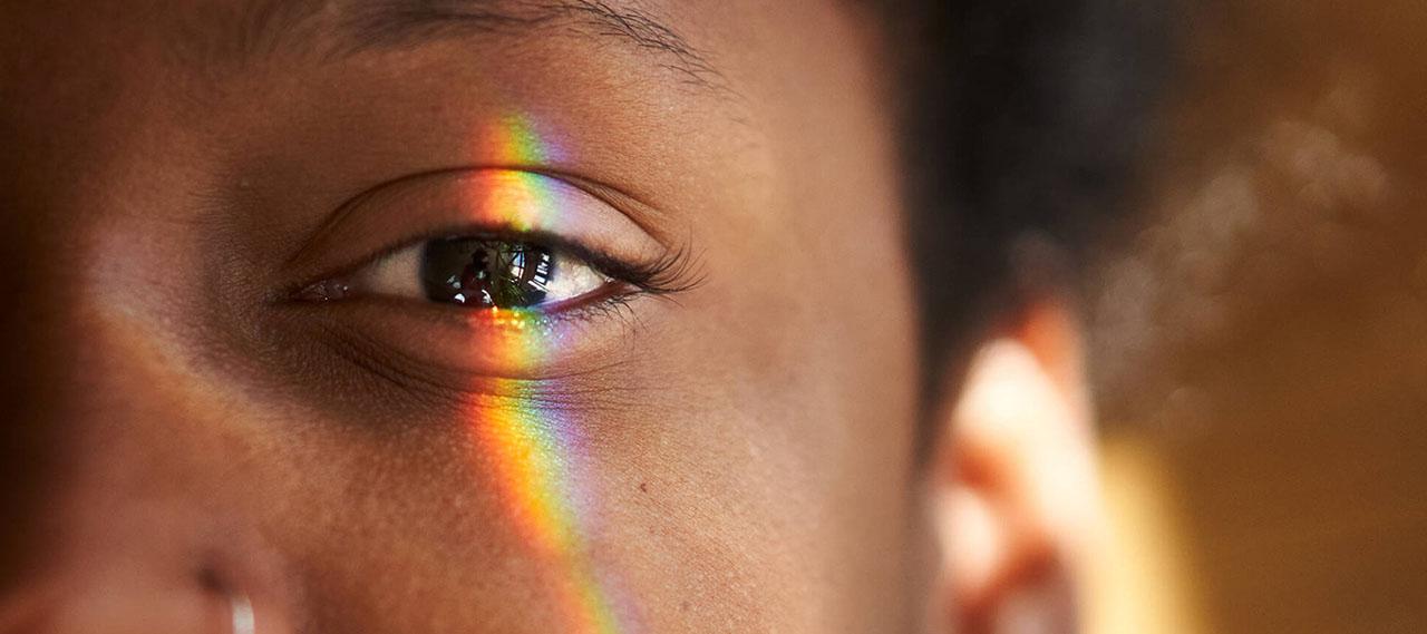 关闭-up of a Black person's eye with a multicolored light falling on it to illustrate how retinal ganglion cells function.